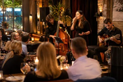 Zangeres met contrabas en gitaar speelt voor luisterend restaurantpubliek bij kaarslicht